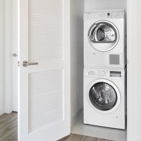 Open closet showing stacked washer and dryer machines